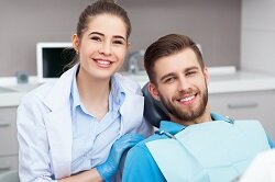 female dentist posing and smiling with male patient in office Woburn, MA dentist and dental care